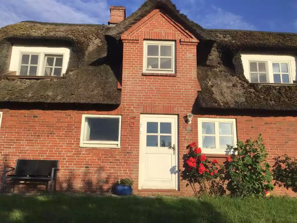 Reetgedecktes Haus mit Eingangsbereich und blühenden Rosen