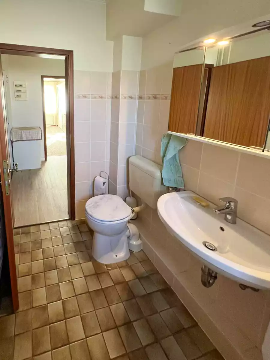Badezimmer mit WC, Waschbecken und Fliesen in Wohnung in Husum