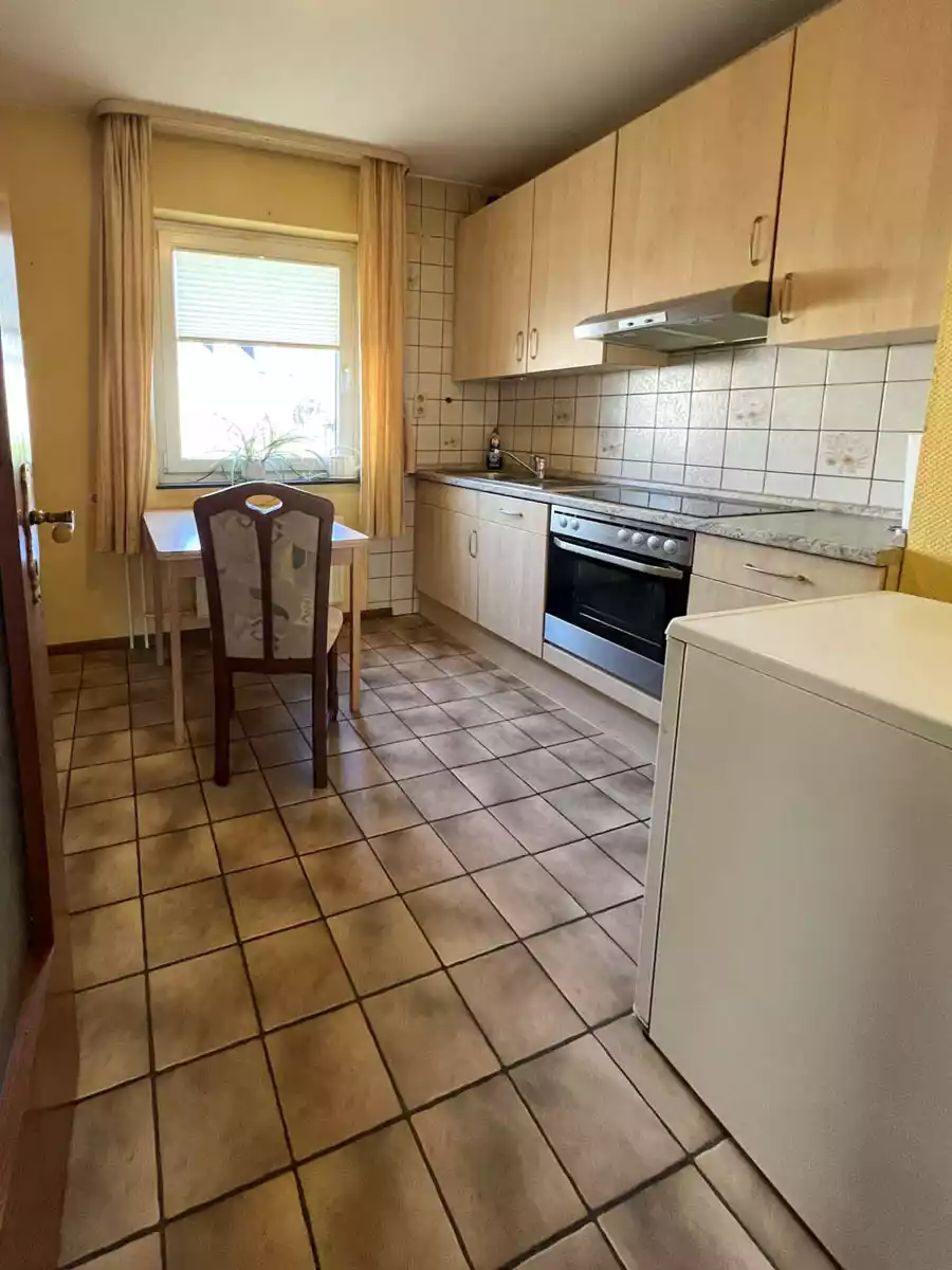 Küche mit Einbauküche, Fenster und gefliestem Boden in Eigentumswohnung in Husum