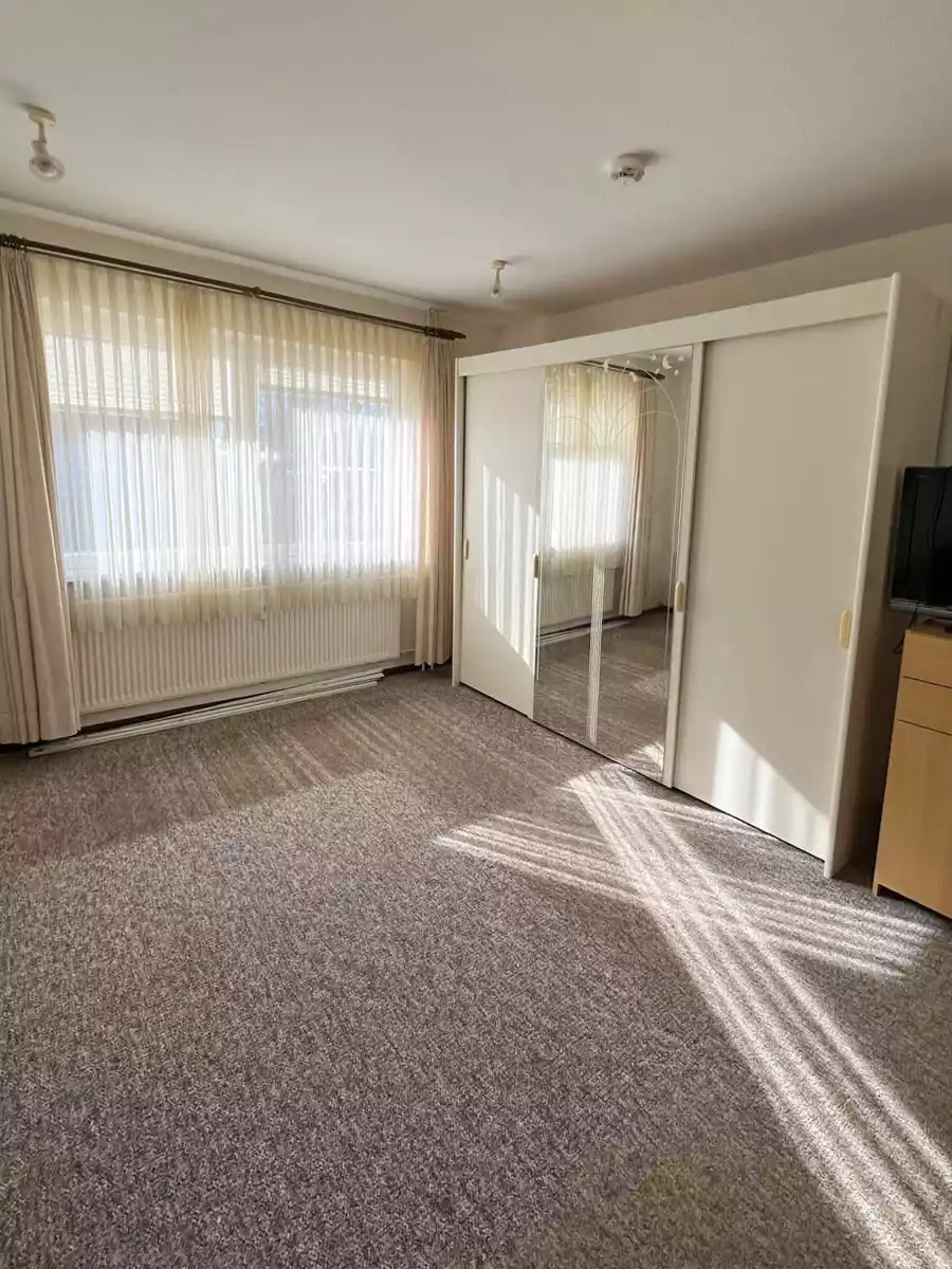 Schlafzimmer mit großem Fenster und Schrank in Wohnung in Husum