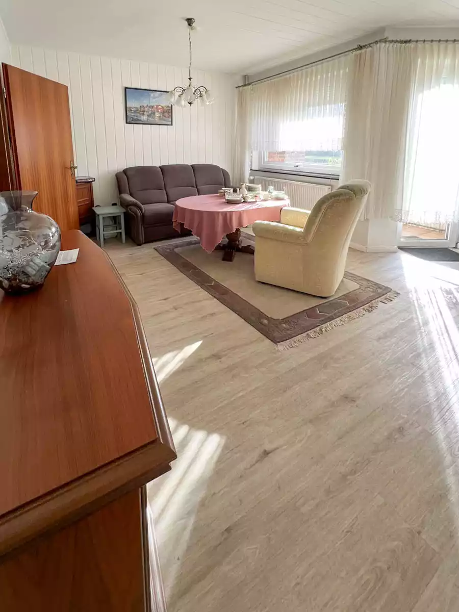 Helles Wohnzimmer mit Couch, Sessel und großen Fenstern in Husum