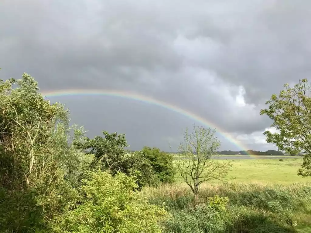 Weitblick über die Landschaft mit Regenbogen am Himmel